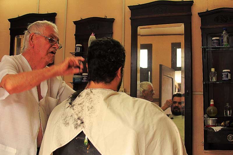 Homem cortando cabelo em uma Barbearia.